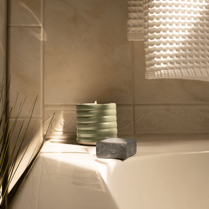 Clean Candle and soap on a bathtub ledge with tiled wall in the background