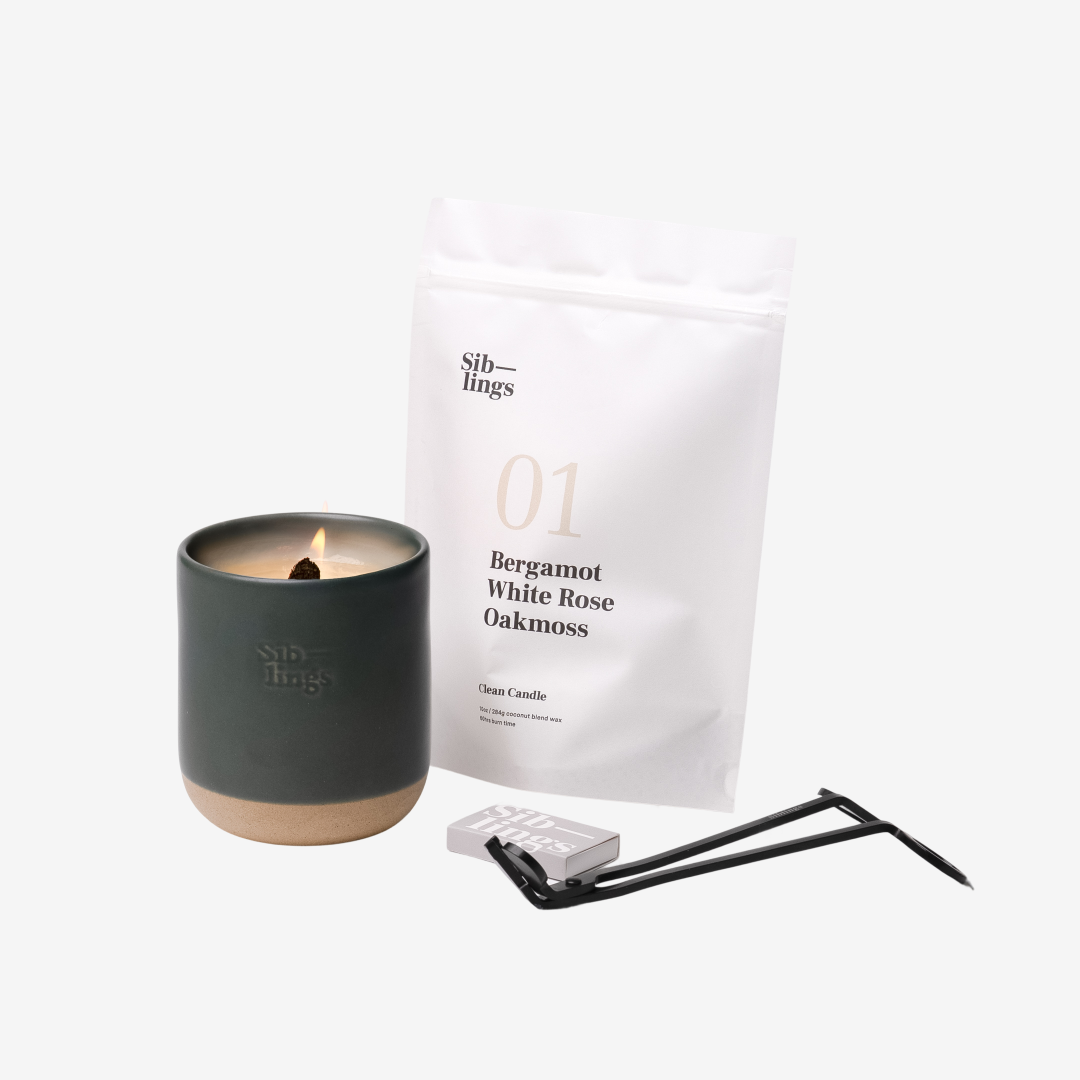 Siblings No. 01 candle starter set with Evergreen vessel, compostable wax refill bag (Bergamot, White Rose, Oakmoss), and black wick trimmer, showcasing an eco-friendly refill kit.