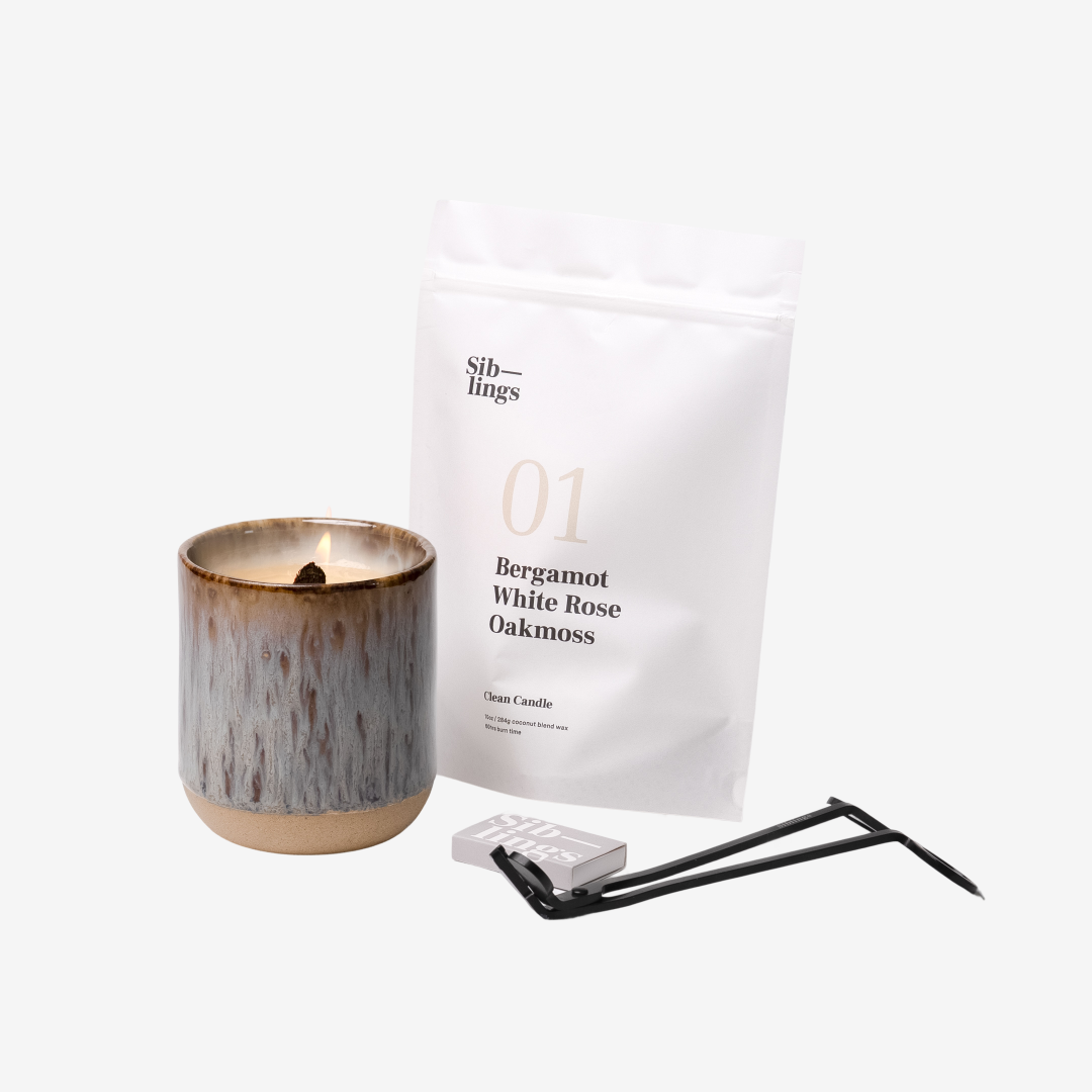 Siblings No. 01 candle starter set with Earth vessel, compostable wax refill bag (Bergamot, White Rose, Oakmoss), and black wick trimmer, showcasing an eco-friendly refill kit.