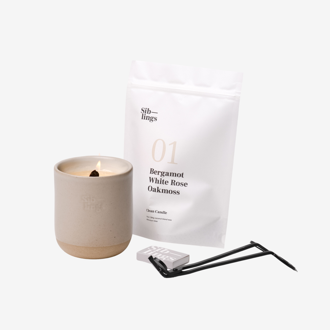 Siblings No. 01 candle starter set with Sand vessel, compostable wax refill bag (Bergamot, White Rose, Oakmoss), and black wick trimmer, showcasing an eco-friendly refill kit.