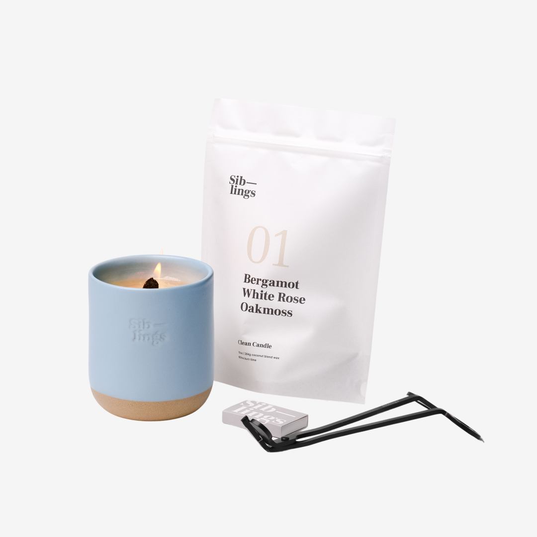 Siblings No. 01 candle starter set with Sky vessel, compostable wax refill bag (Bergamot, White Rose, Oakmoss), and black wick trimmer, showcasing an eco-friendly refill kit.
