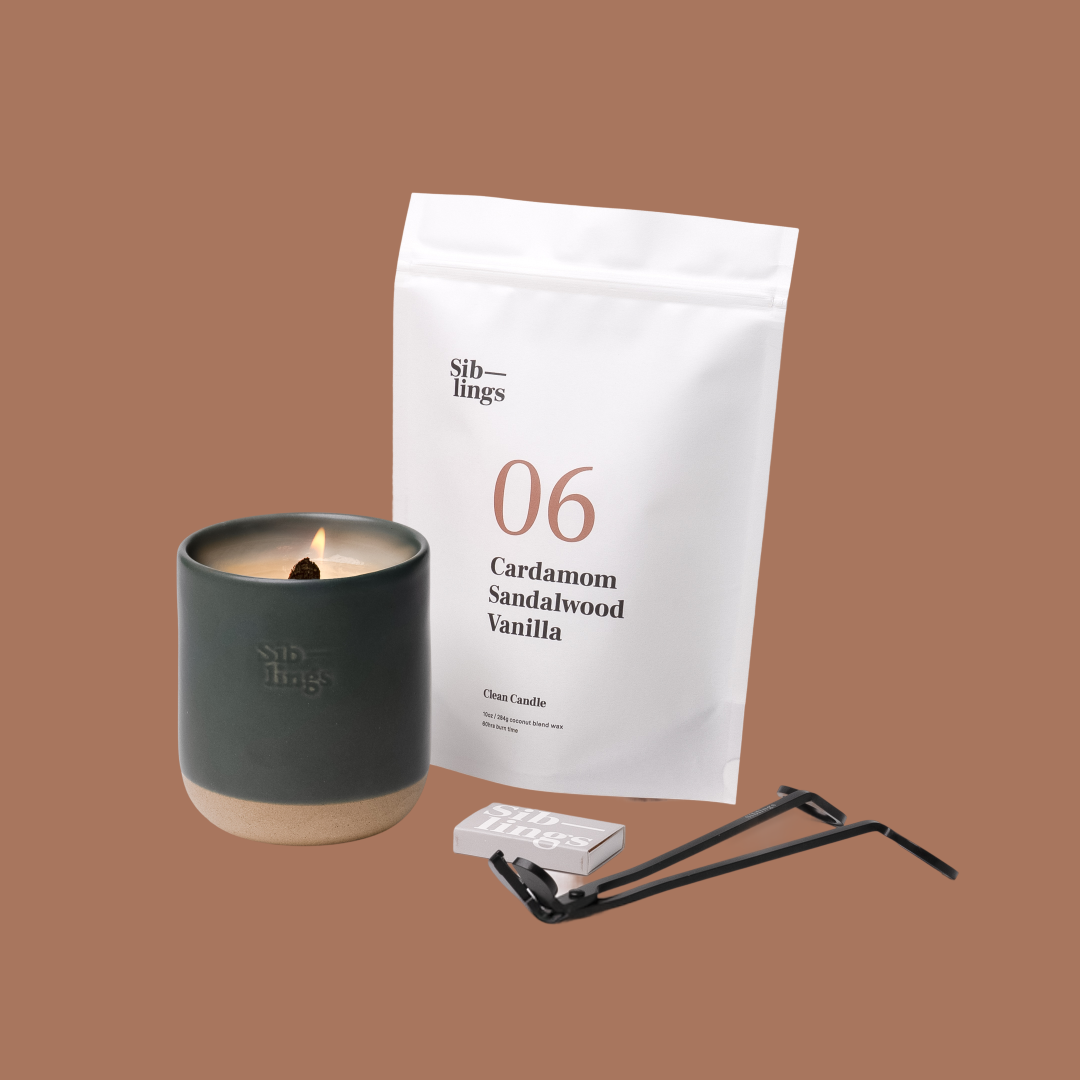 Siblings No. 06 candle starter set with Evergreen vessel, compostable wax refill bag (Cardamom, Sandalwood, Vanilla ), and black wick trimmer, showcasing an eco-friendly refill kit.