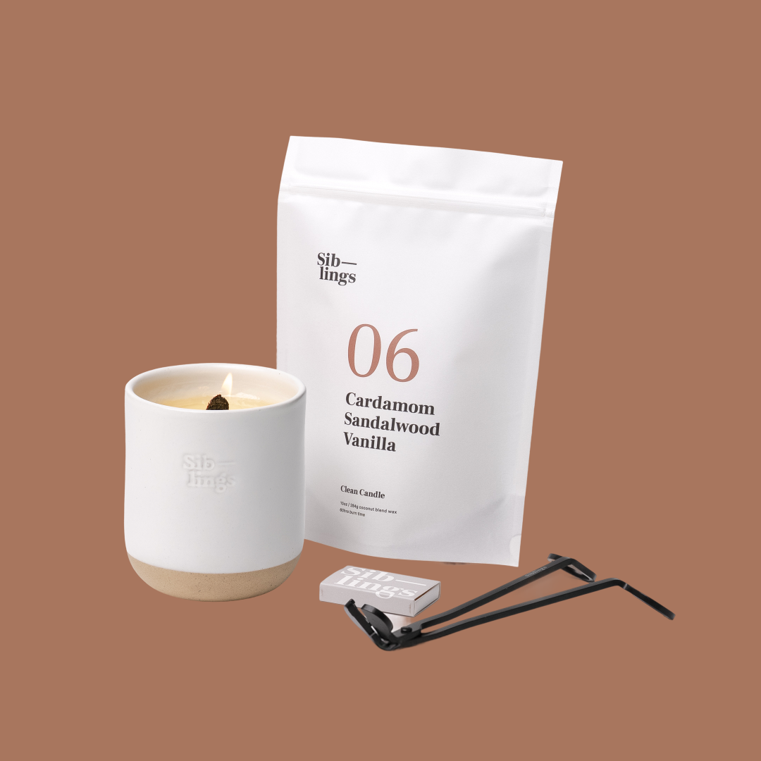 Siblings No. 06 candle starter set with White Cloud vessel, compostable wax refill bag (Cardamom, Sandalwood, Vanilla), and black wick trimmer, showcasing an eco-friendly refill kit.