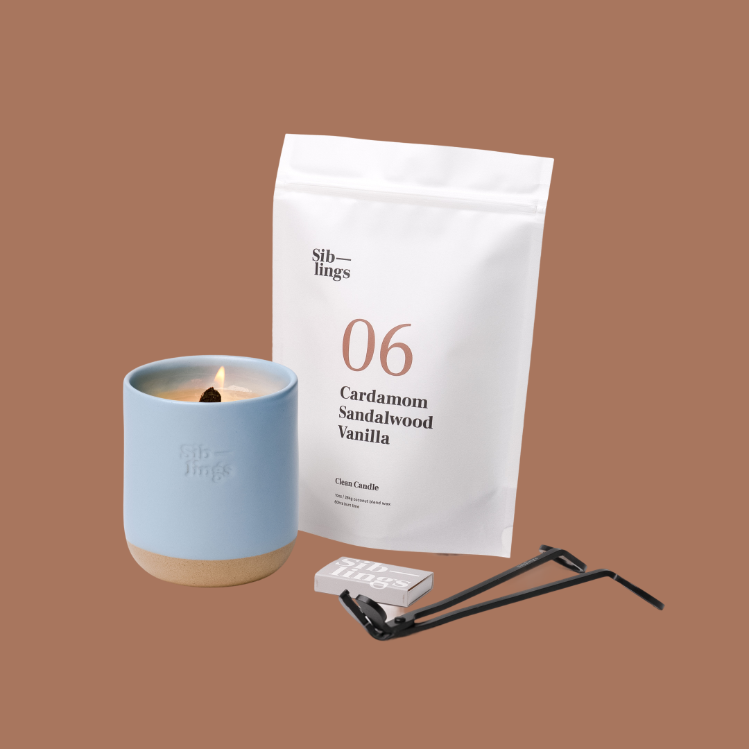 Siblings No. 06 candle starter set with Sky vessel, compostable wax refill bag (Cardamom, Sandalwood, Vanilla ), and black wick trimmer, showcasing an eco-friendly refill kit.